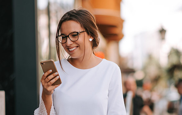 Woman looking at phone while walking down street.